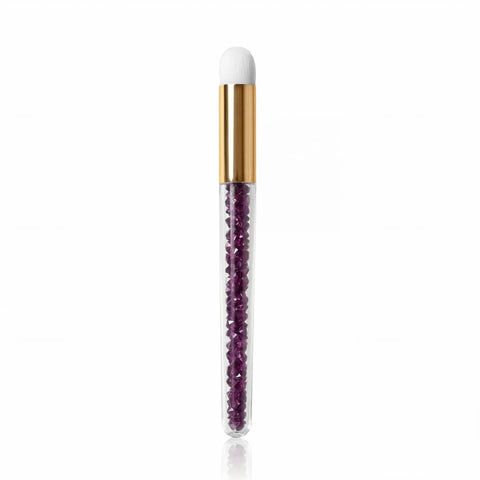 Violette Wimpern-Reinigungsbürste mit weißem Bürstenkopf, goldenem Metallhals und transparentem Griff mit violetten Kristallsteinen für die professionelle Reinigung von Wimpernverlängerungen.